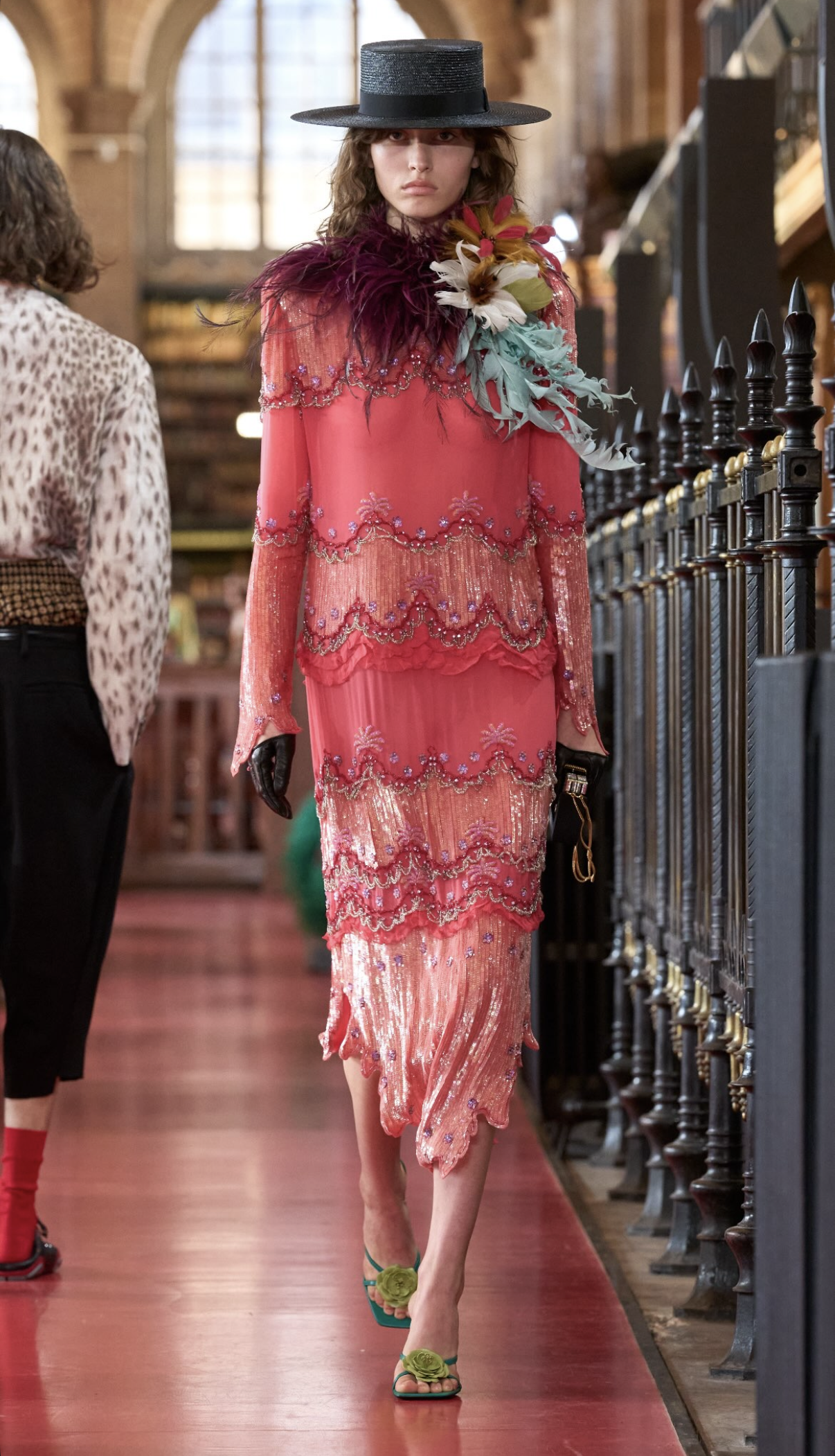 Modelo con sombrero negro y vestido rosa de pedrería y plumas